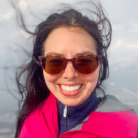 Layla Messner, founder of the Chameleon Collective A smiling autistic founder in a pink jacket with her dark hair blowing in the wind