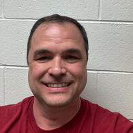 A smiling autistic man A smiling man with dark hair, wearing a red t-shirt